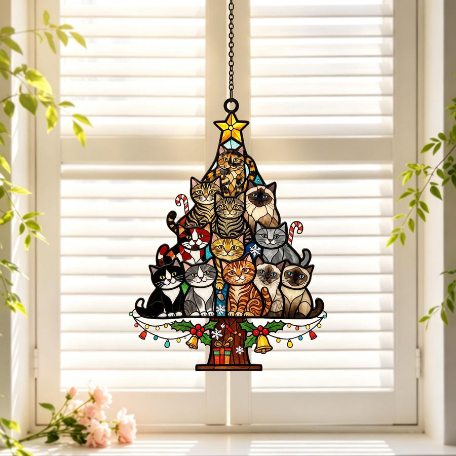 A stained glass suncatcher shaped like a Christmas tree, featuring a stack of various cat breeds in different colors. The tree is topped with a yellow star, decorated with candy canes, bells, and a gift box at the base, hanging by a chain.