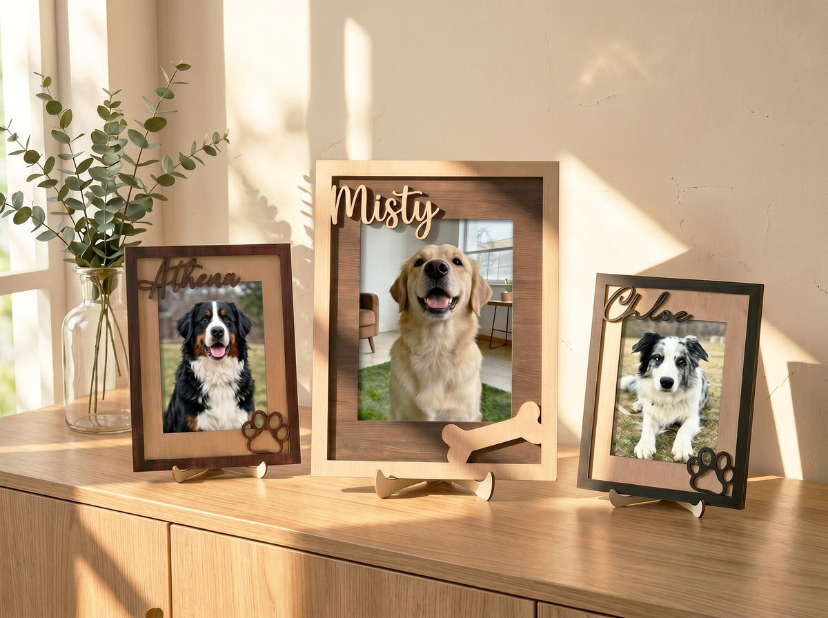 Three rectangular wooden picture frames featuring custom names in script font. The frames display photos of dogs and include decorative wooden cutouts of paw prints and a bone. The frames have a two-tone brown finish and stands.