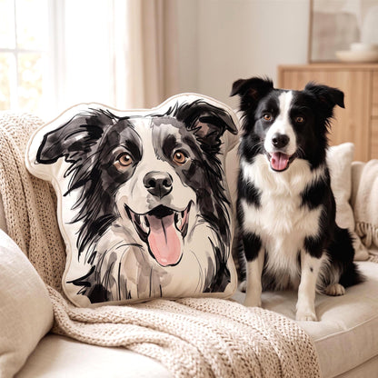 A square-shaped throw pillow featuring a detailed watercolor-style illustration of a black and white Border Collie with its tongue out, matching the appearance of the live Border Collie sitting next to it on the sofa.