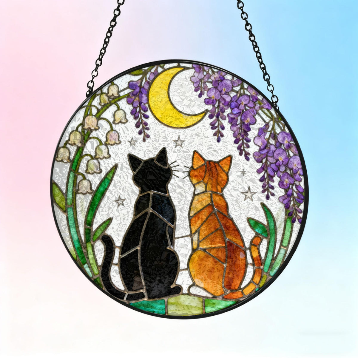 Round stained glass window art featuring two cats, one black and one orange, gazing at a yellow crescent moon. The design includes purple wisteria, white flowers, and stars, with a black chain for hanging.