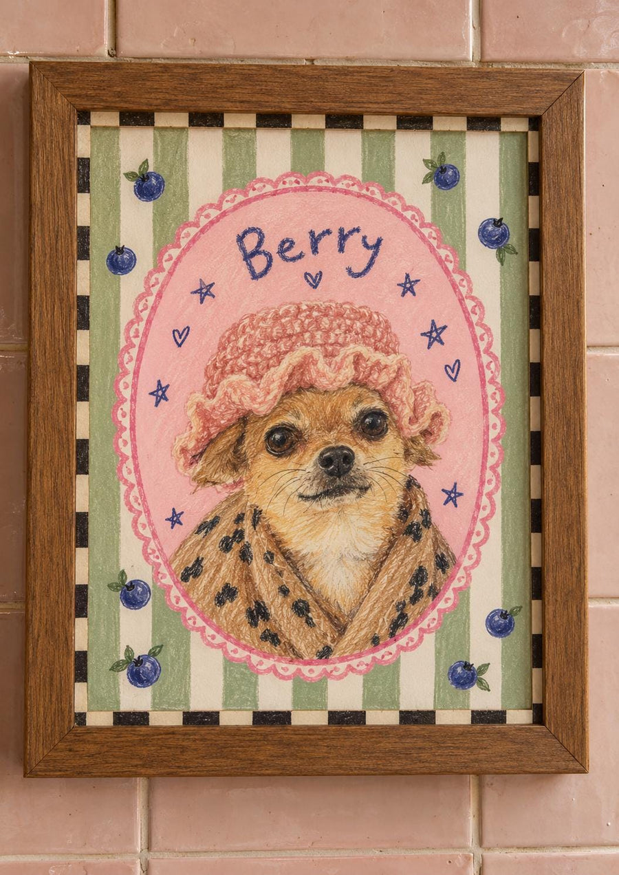 A framed drawing of a tan dog wearing a pink crocheted hat and a brown leopard print robe. The dog is centered in a pink oval frame with the word Berry written above it. The background features green stripes, blueberries, and a black and white checkered border.