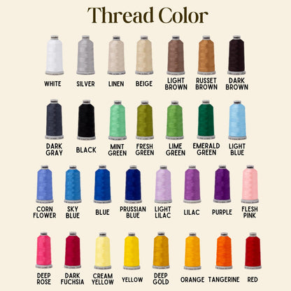 A color chart titled Thread Color displaying twenty-eight spools of embroidery thread in various shades including white, silver, linen, beige, light brown, russet brown, dark brown, dark gray, black, mint, fresh, lime, emerald, light blue, cornflower, sky blue, blue, prussian blue, light lilac, lilac, purple, flesh pink, deep rose, dark fuchsia, cream yellow, yellow, deep gold, orange, tangerine, and red.