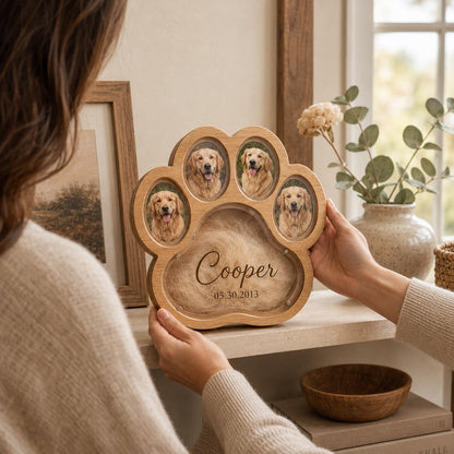 A light-colored wooden paw-shaped picture frame featuring four oval photo slots containing images of a golden retriever. The center of the frame displays the name Cooper and the date 05.30.2013 printed over a textured tan material.