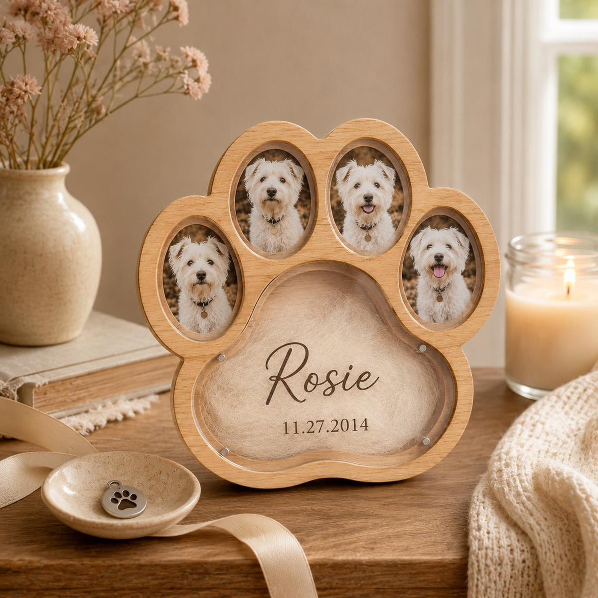 A light-colored wooden paw-shaped photo frame featuring three oval openings for dog portraits and a central area engraved with the name Rosie and the date 11.27.2014. The frame includes a small matching paw-print charm in a dish.
