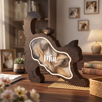 A dark brown wooden cat-shaped shadow box with a clear front panel. The name Miu is printed in white script on the glass. The interior contains light-colored fur, and a small wooden heart with a paw print sits on the cat's back.
