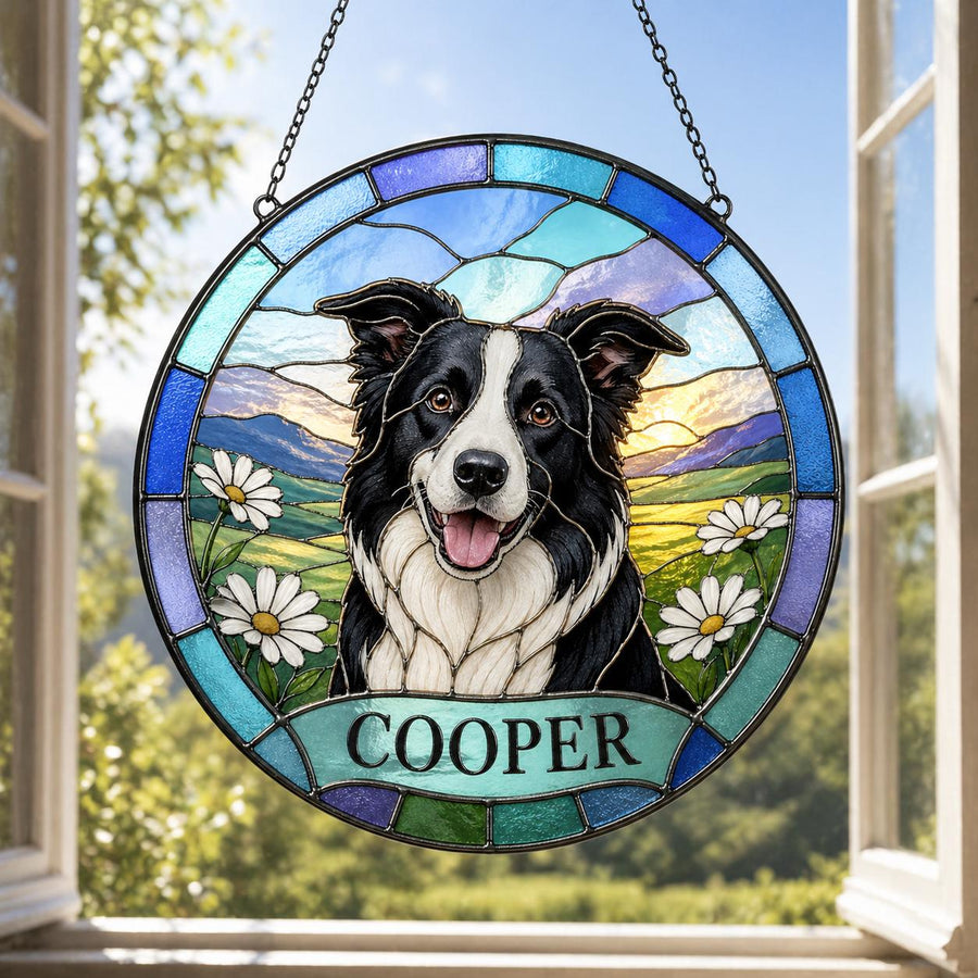 A round stained glass window featuring a black and white Border Collie dog with the name "COOPER" below. The dog is set against a landscape of green fields, white daisies, and a blue sky.