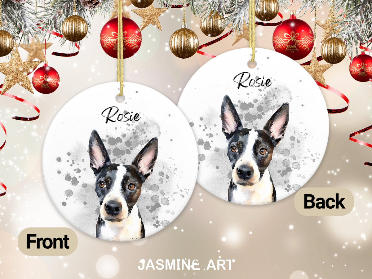 Two round Christmas ornaments with a dog portrait. The dog is black and white with the name "Rosie" above the image. The ornaments are hanging with gold string, with Christmas decorations in the background.