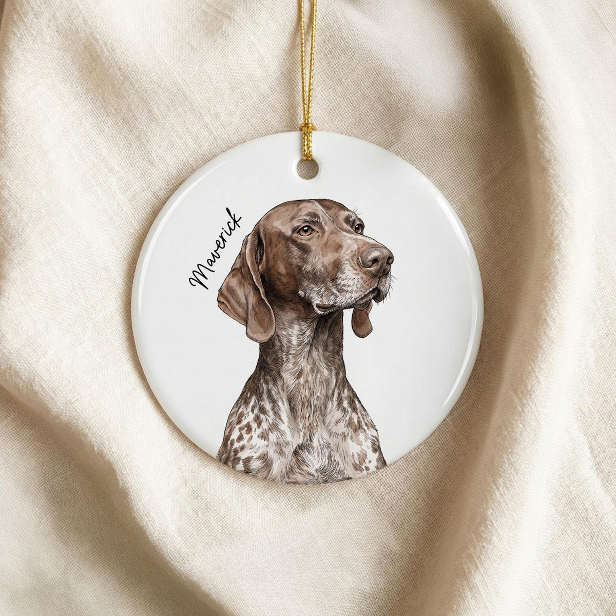 A round white ceramic ornament featuring a detailed illustration of a brown and white German Shorthaired Pointer dog. The name Maverick is printed in black script to the left of the dog. A gold string is attached for hanging.