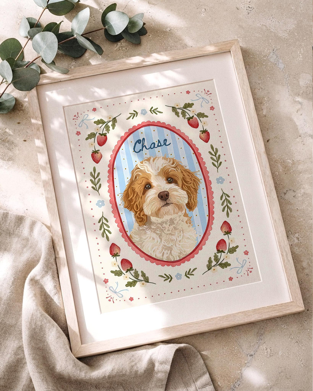 A framed illustration of a brown and white dog named Chase, centered in a blue striped oval with a pink scalloped border. The artwork features a cream background decorated with red strawberries, green leaves, and small blue bows.