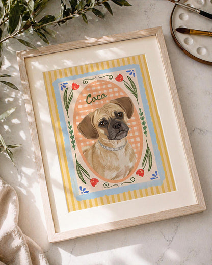 A framed art print featuring a tan dog with a dark muzzle wearing a silver collar, centered in an oval frame against a peach gingham background. The border includes yellow stripes, blue accents, and red tulip illustrations with the name Coco.