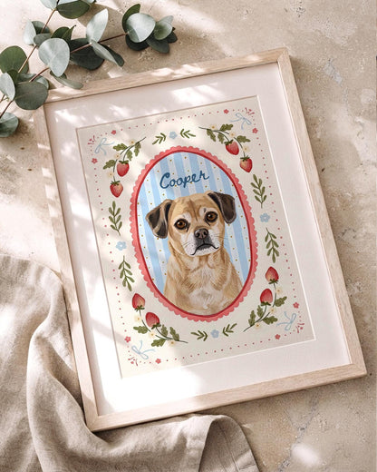 A framed illustration of a tan dog with dark ears, centered in a blue and white striped oval frame with a red scalloped border. The name Cooper is written above the dog. The border features red strawberries, green leaves, and blue bows.
