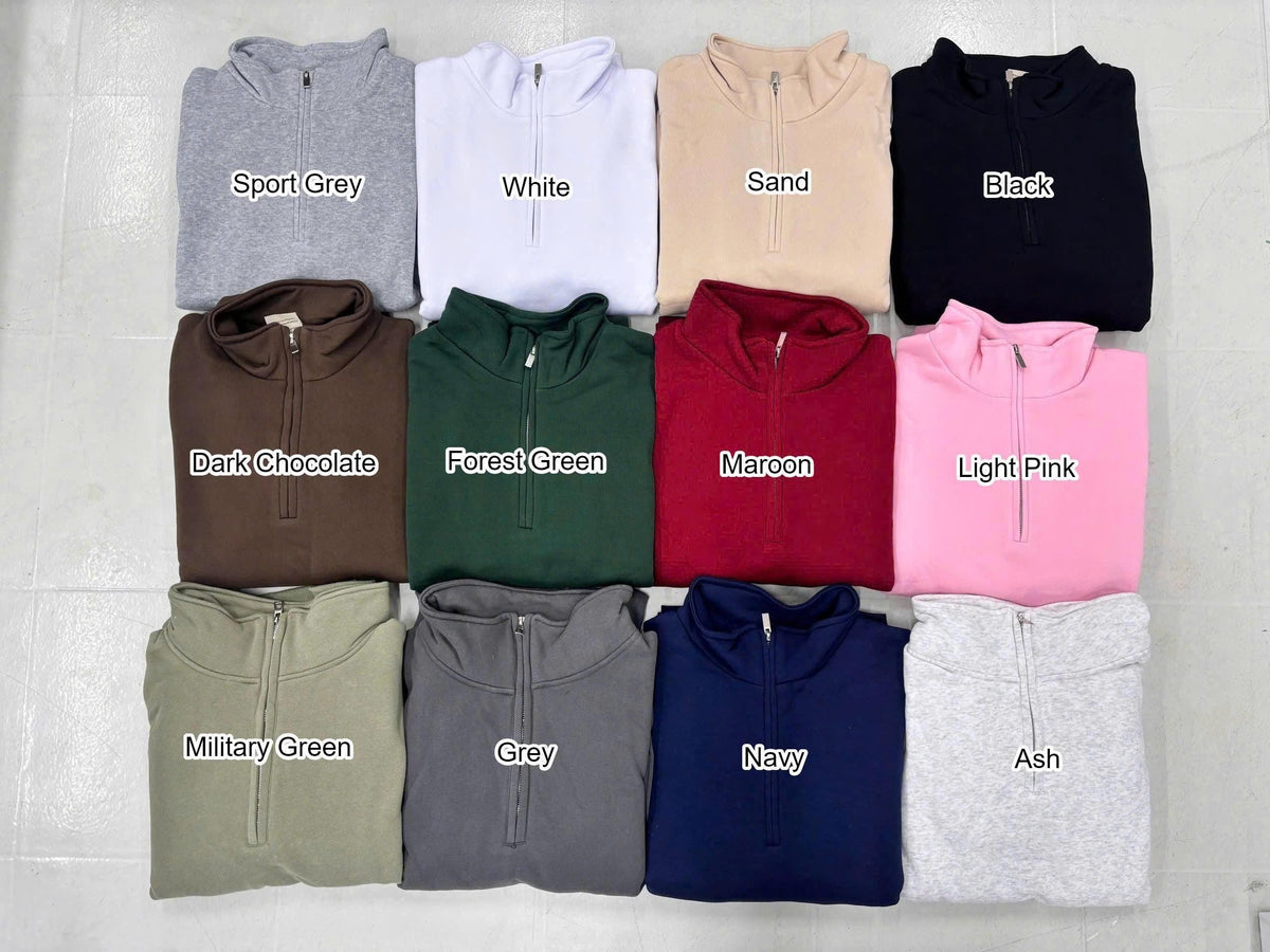 A collection of twelve quarter-zip sweatshirts arranged in a grid, featuring colors labeled as Sport Grey, White, Sand, Black, Dark Chocolate, Forest Green, Maroon, Light Pink, Military Green, Grey, Navy, and Ash, each with a metal zipper.