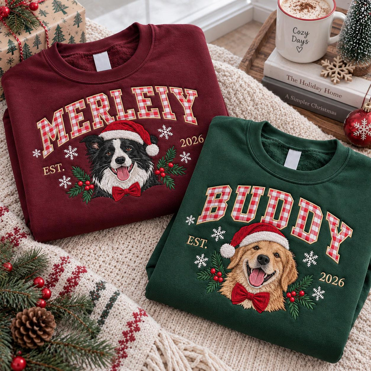 A maroon sweatshirt with the name MERLEIY and a green sweatshirt with the name BUDDY. Both feature embroidered dog portraits wearing Santa hats and red bow ties, surrounded by holly, berries, and snowflakes, with EST. 2026.