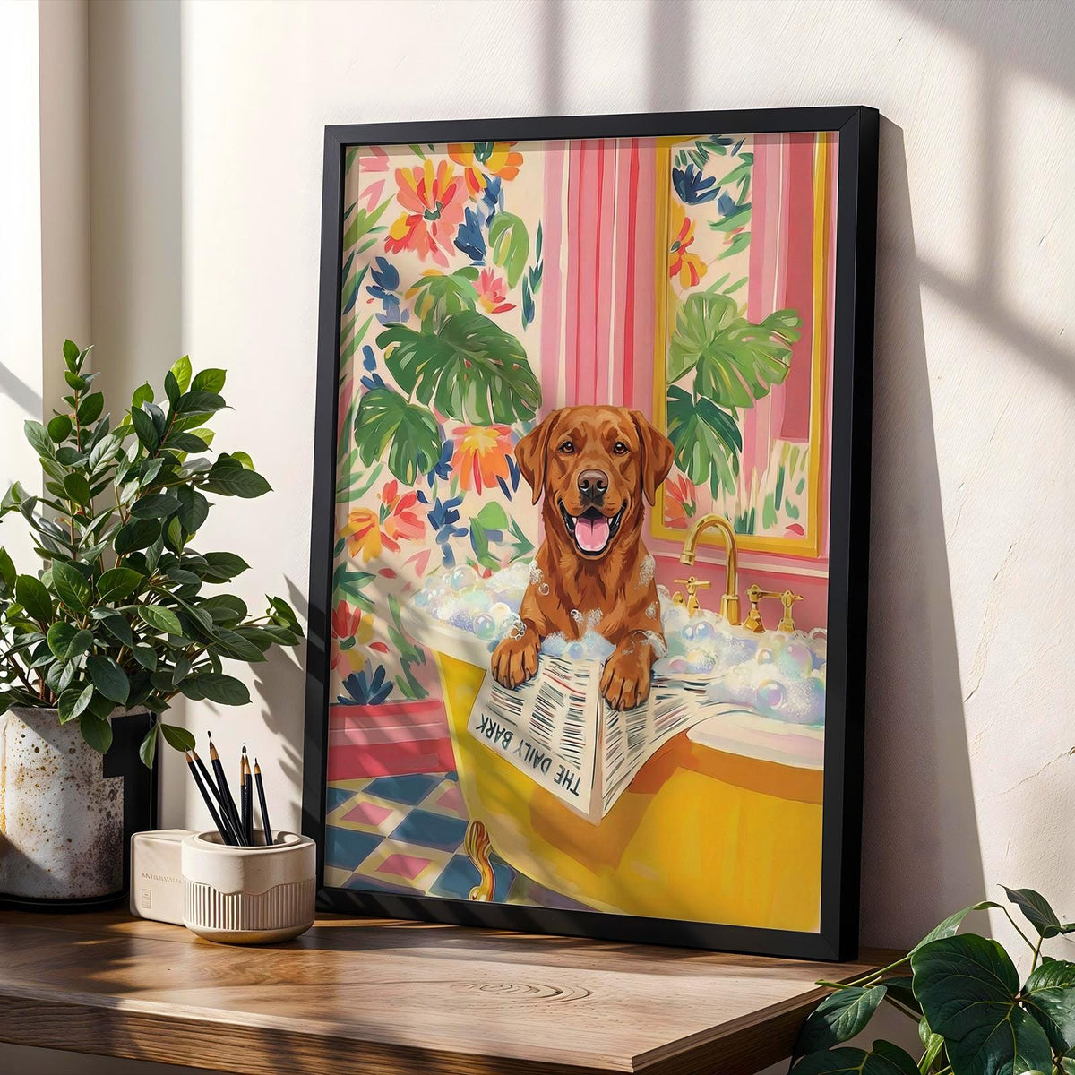 Framed art print featuring a brown Labrador Retriever in a yellow bathtub filled with bubbles. The dog is holding a newspaper that reads "THE DAILY BARK." The background includes floral wallpaper and a pink striped curtain.