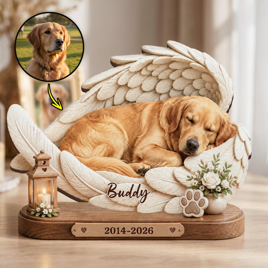 A memorial sculpture featuring a golden retriever sleeping within large white angel wings. The base is wood with a plaque reading 2014-2026. The name Buddy is inscribed on the wing. Includes a small lantern and a paw print icon.