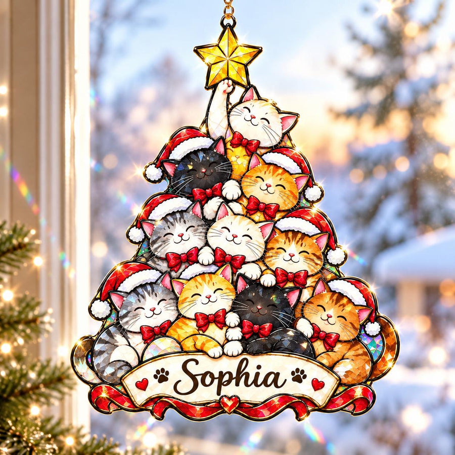 A stained glass-style hanging ornament shaped like a Christmas tree, featuring multiple cats wearing red Santa hats and bows. A yellow star sits at the top. A banner at the bottom displays the name Sophia with paw prints.