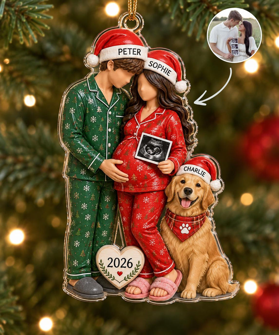 A clear acrylic Christmas ornament featuring a couple in green and red snowflake pajamas with Santa hats labeled Peter and Sophie. The pregnant person holds an ultrasound image. A golden retriever named Charlie sits beside them.