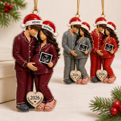 A set of three flat acrylic Christmas ornaments featuring a couple in pajamas and Santa hats. Each ornament shows a pregnant person holding an ultrasound photo, with names Henry and Sophia on hats and the year 2026 on a heart-shaped tag.