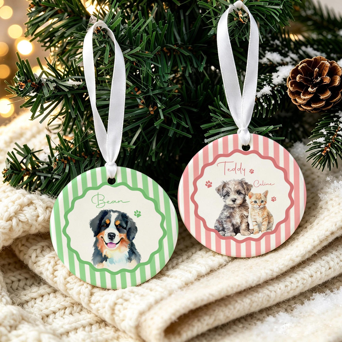 Two round ceramic ornaments with white ribbon hangers. One features green stripes, a scalloped border, and a Bernese Mountain Dog illustration with the name Bean. The other has pink stripes, a scalloped border, and a puppy and kitten with the names Teddy and Caline.