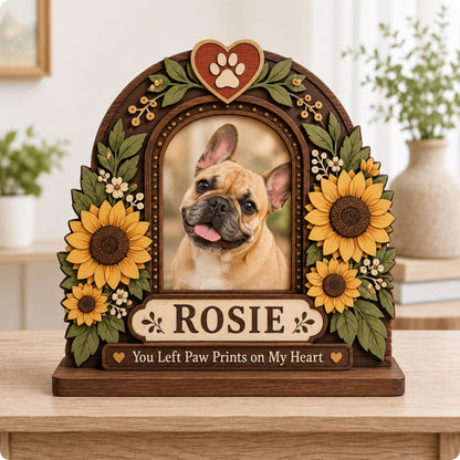 A wooden arched photo frame featuring a portrait of a fawn French Bulldog. The frame is decorated with layered sunflowers, green leaves, and a heart with a paw print. It includes the name ROSIE and the text You Left Paw Prints on My Heart.