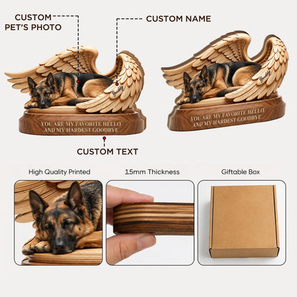 A wooden memorial plaque featuring a German Shepherd resting between two carved angel wings. The base includes the engraved text, "YOU ARE MY FAVORITE HELLO AND MY HARDEST GOODBYE," and a custom name. It has a 15mm thickness.