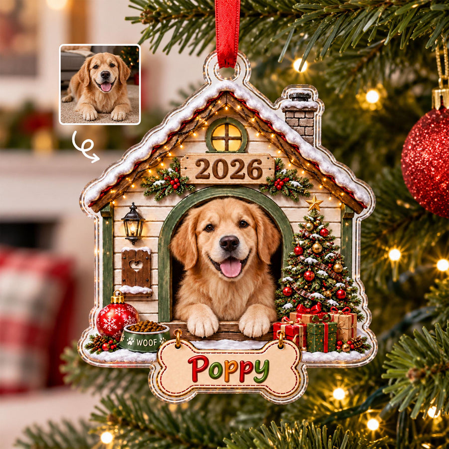 A house-shaped Christmas ornament featuring a golden retriever inside a doghouse, a decorated Christmas tree, a red ornament, a bowl labeled "WOOF," the year "2026," and a bone-shaped sign with the name "Poppy" hanging from the bottom.