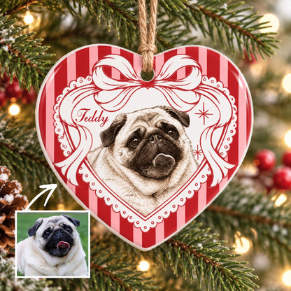 A heart-shaped ceramic ornament featuring a portrait of a fawn pug with a black muzzle and tongue sticking out. The design includes a red and white striped background, a white ribbon border, and the name Teddy written in script.