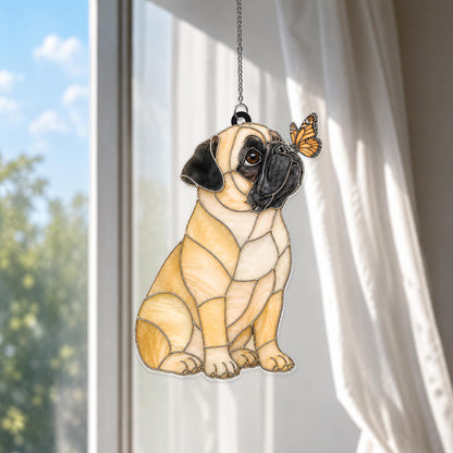 A stained glass suncatcher shaped like a fawn-colored pug with a black muzzle and ears, sitting in profile. A small orange and black monarch butterfly rests on the pug's nose. The piece is suspended by a silver-toned metal chain.