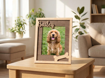 A rectangular wooden picture frame with a light wood outer border and a dark wood inner frame. The name Bailey is cut out in script lettering at the top, and a bone-shaped cutout is attached to the bottom right corner of the frame.