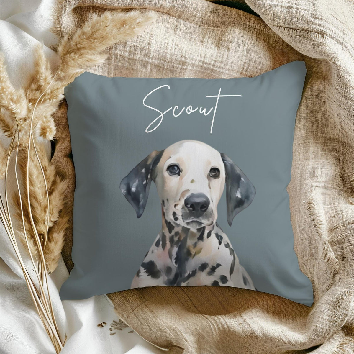 A blue throw pillow with a watercolor illustration of a Dalmatian dog. The dog's name, "Scout", is written in white cursive above the dog.