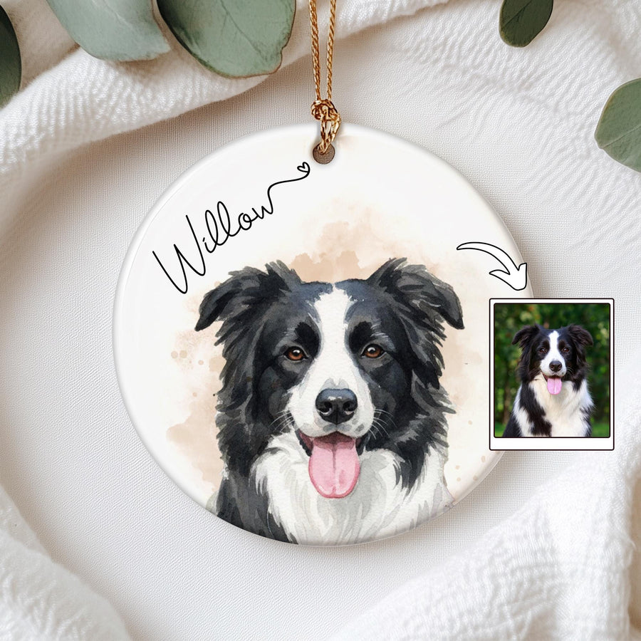 A round, white ceramic ornament featuring a watercolor-style portrait of a black and white dog with its tongue out. The name "Willow" is written in cursive. A small photo of the dog is in the corner. A gold string is attached for hanging.