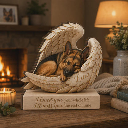 A wooden memorial sculpture featuring a German Shepherd dog sleeping inside a pair of carved angel wings. The name Luna is engraved on the wing, and the base is inscribed with the text: I loved you your whole life I'll miss you the rest of mine.