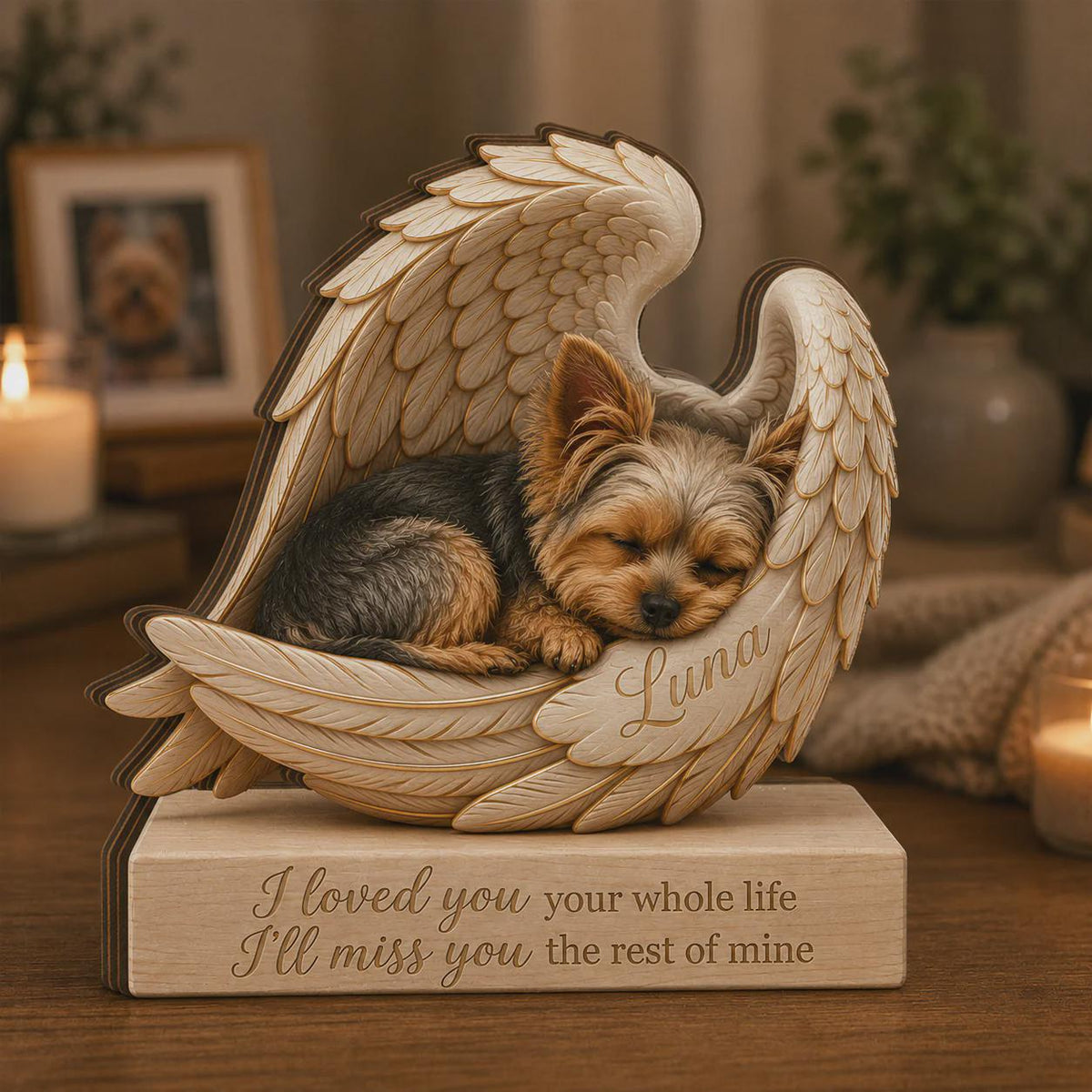 A wooden memorial sculpture featuring a sleeping Yorkshire Terrier nestled within carved angel wings. The name Luna is engraved on the wing, and the base displays the text: I loved you your whole life, I'll miss you the rest of mine.