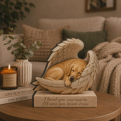 A tan dog figurine sleeping inside a pair of large, detailed angel wings. The name Luna is engraved on the wing. The figurine rests on a rectangular base with the engraved text: I loved you your whole life I'll miss you the rest of mine.