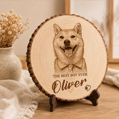 A circular wooden plaque with natural bark edges, featuring a laser-engraved portrait of a dog wearing a collared shirt and tie. The text reads THE BEST BOY EVER, the name Oliver, and a small heart with a paw print icon.