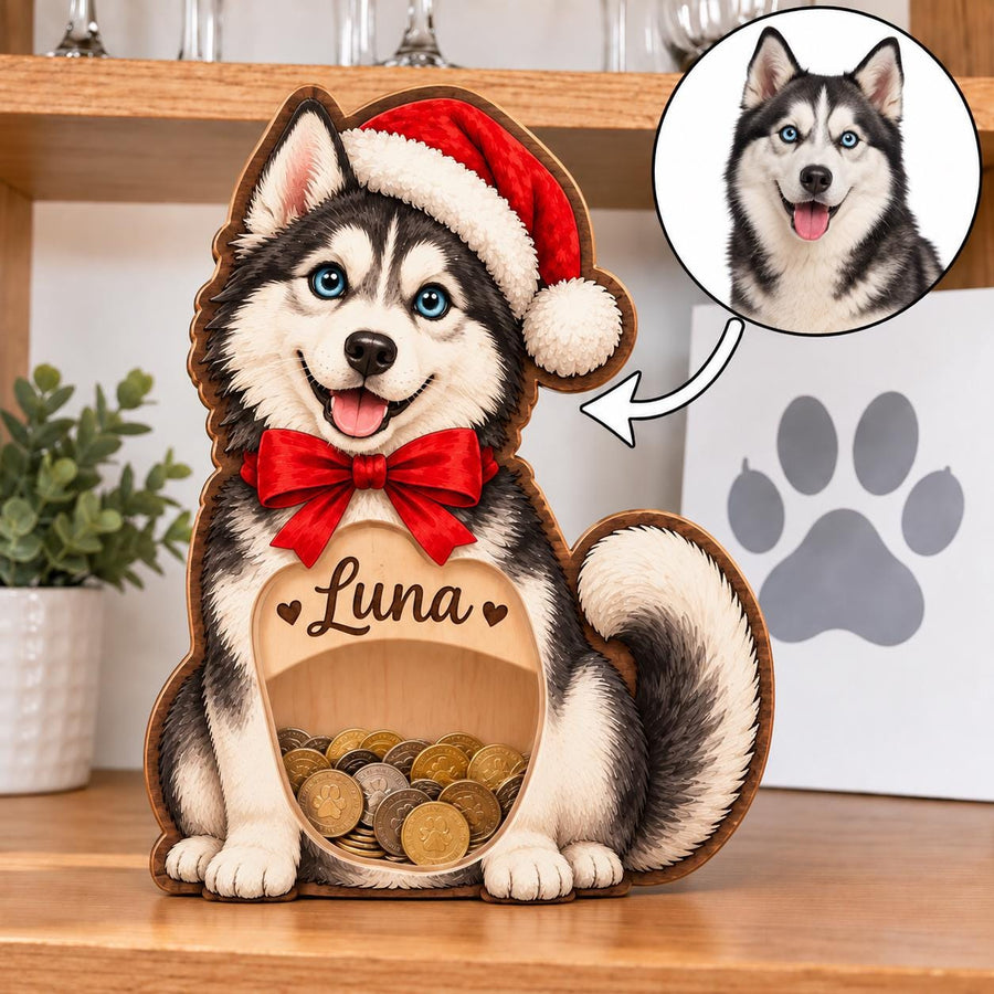 A wooden piggy bank shaped like a Siberian Husky wearing a red Santa hat and a red bow tie. The front features a clear window filled with coins and the name Luna engraved above it. A circular inset shows a photo of a real husky.